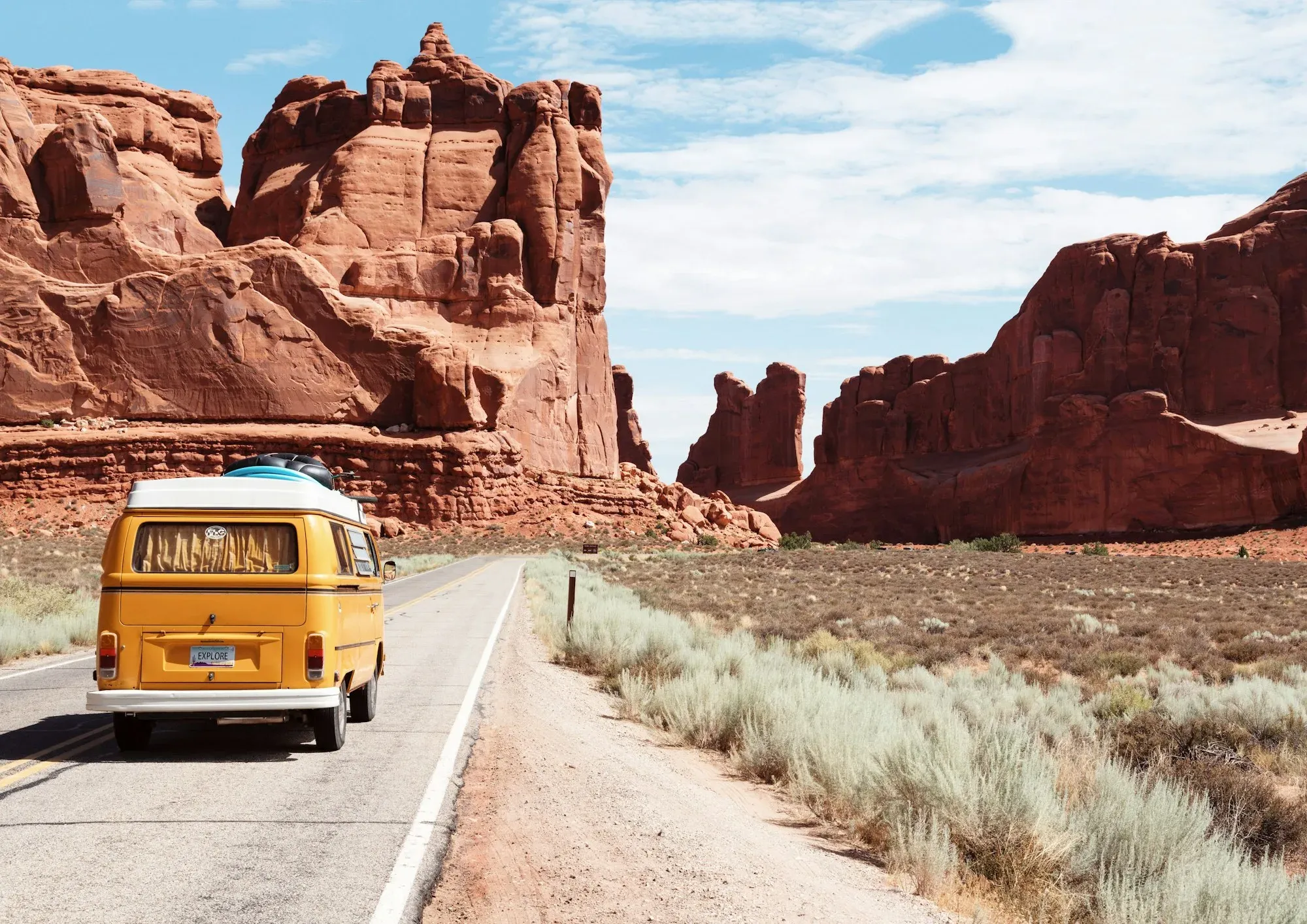 Campervan on the road through a vast red landscape